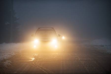 19014564-bright-headlights-of-a-car-driving-on-foggy-winter-road